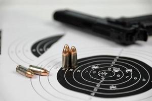 Gun and many bullets shooting targets on white table in shooting range polygon. Training for aiming and shooting photo