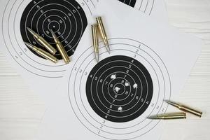 Many bullets on shooting targets on white table in shooting range polygon. Training for aiming and shooting photo