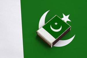 Pakistan flag  is pictured on a matchbox that lies on a large flag photo