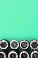 Several photographic lenses lie on a bright turquoise background. Copy space photo