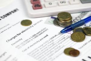 Calculator and Euro bills with pen on european electricity bill. Concept of saving money by using energy savings led light bulbs and electric bill payment photo