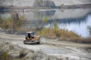 agregado de cantera con maquinaria pesada. Excavadora de oruga con retroexcavadora que conduce a la cantera del sitio de construcción foto