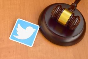 KHARKIV, UKRAINE - MAY 2, 2021 Twitter paper logo lies with wooden judge gavel. Entertainment lawsuit concept photo