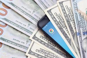 KHARKIV, UKRAINE - MAY 2, 2021 Smartphone screen with Google chrome app and lot of hundred dollar bills. Business and social networking concept photo
