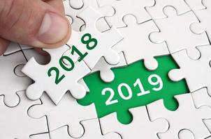 The human hand fills the last missing elements of the surface from the jigsaw puzzle. Happy new 2019 year photo