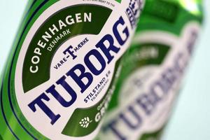 KHARKOV, UKRAINE - DECEMBER 8, 2020 Aluminium cans of green Tuborg beer on wooden background. Tuborg is Danish brewing company founded in 1873 photo