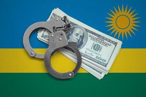 Rwanda flag  with handcuffs and a bundle of dollars. Currency corruption in the country. Financial crimes photo