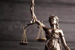The Statue of Justice - lady justice or justitia the Roman goddess of Justice. Statue on black wooden wall. Concept of judicial trial, courtroom process and lawyers work photo