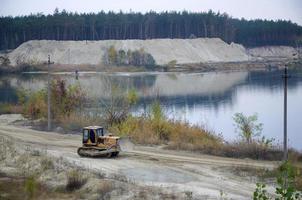 agregado de cantera con maquinaria pesada. Excavadora de oruga con retroexcavadora que conduce a la cantera del sitio de construcción foto