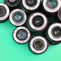 Several photographic lenses lie on a bright turquoise background. Copy space photo