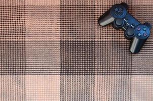 Video game controller lies on a checkered plaid photo