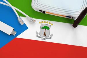 Equatorial Guinea flag depicted on table with internet rj45 cable, wireless usb wifi adapter and router. Internet connection concept photo