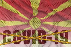 Macedonia flag and Covid-19 inscription with orange quarantine border tape. Coronavirus or 2019-nCov virus concept photo