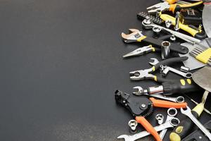 Handyman tool kit on black wooden table. Many wrenches and screwdrivers, pilers and other tools for any types of repair or construction works. Repairman tools photo