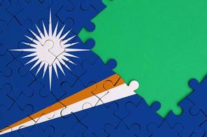 Marshall Islands flag  is depicted on a completed jigsaw puzzle with free green copy space on the right side photo