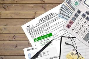 IRS form W-7 Application for IRS individual taxpayer identification number lies on flat lay office table and ready to fill. U.S. Internal revenue services paperwork concept photo