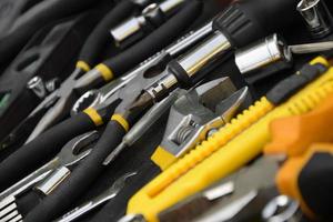 Handyman tool kit on black wooden table. Many wrenches and screwdrivers, pilers and other tools for any types of repair or construction works. Repairman tools photo