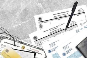 USCIS form I-485 Application to register permanent residence or adjust status and N-400 Application for naturalization with Certificate of naturalization lies on office table photo
