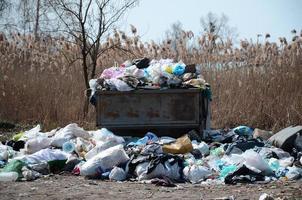 el bote de basura está lleno de basura y desechos. retiro intempestivo de basura en zonas pobladas foto