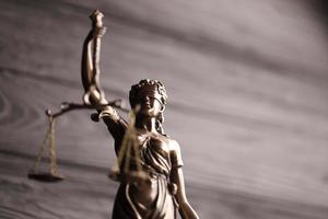 The Statue of Justice - lady justice or justitia the Roman goddess of Justice. Statue on black wooden wall. Concept of judicial trial, courtroom process and lawyers work photo