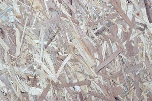 OSB boards made of brown wood chips sanded into a wooden background. Top view of OSB wood veneer background surface photo