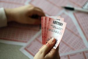 Filling out a lottery ticket. A young woman holds the lottery ticket with complete row of numbers on the lottery blank sheets background. photo