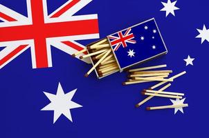 Australia flag  is shown on an open matchbox, from which several matches fall and lies on a large flag photo