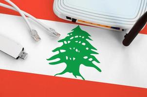 Lebanon flag depicted on table with internet rj45 cable, wireless usb wifi adapter and router. Internet connection concept photo