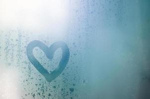 The heart is painted on the misted glass in winter photo