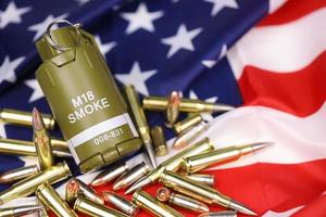 M18 smoke grenade and many yellow bullets and cartridges on United States flag. Concept of gun trafficking on USA territory or spec ops photo