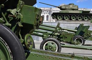 Photo of three guns of the Soviet Union of the Second World War against the background of the green tank T-34