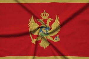 Montenegro flag  is depicted on a sports cloth fabric with many folds. Sport team banner photo