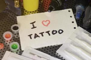 me encanta el tatuaje el texto está escrito en una pequeña hoja de papel entre varios equipos para tatuar foto