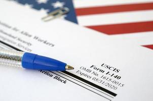 I-140 Immigrant petition for alien workers blank form lies on United States flag with blue pen from Department of Homeland Security photo