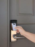 hand holding keycard to scan electronic lock door photo