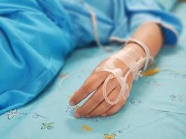 mano de mujer con goteo intravenoso en la cama del paciente foto