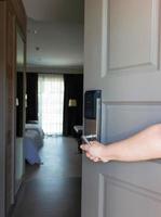 mano sujetando la empuñadura de la puerta para abrir la habitación del hotel foto