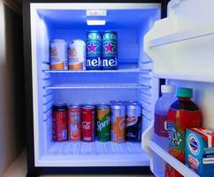 latas de refrescos fríos en mini refrigerador foto