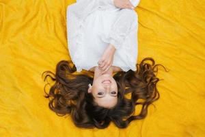 Top view of a happy white girl with a charming snow-white smile on a yellow background photo