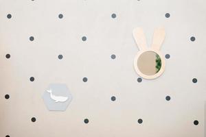 A mirror in the form of a rabbit made of wood hangs on the wall with gray peas photo