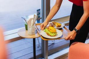 camarera sirviendo sándwich de verduras en una bandeja en el café. foto