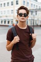 Young handsome man model looks in sunglasses and a backpack travels. photo