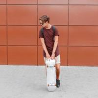 Handsome man posing with skateboard near the wall photo