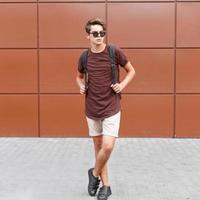 Young handsome man in summer clothes is posing near the wall photo