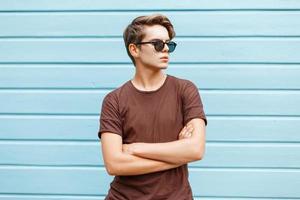 Young stylish handsome man is posing next to a bright blue wall. photo