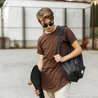 Young handsome guy in stylish clothing walking with a skateboard. photo