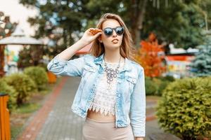 Beautiful girl in sunglasses and  jeans jacket walking in the park attractions photo