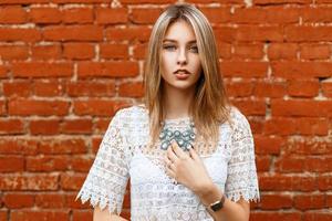 Beautiful girl in white vintage lace blouse with jewelry on a background of bricks photo