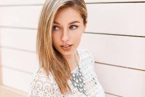 Close-up portrait of a beautiful woman in stylish vintage white lace blouse looks to the side on a background of a wooden wall photo