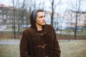 joven con estilo en una vieja chaqueta y gorro de punto en un fondo del parque de otoño foto